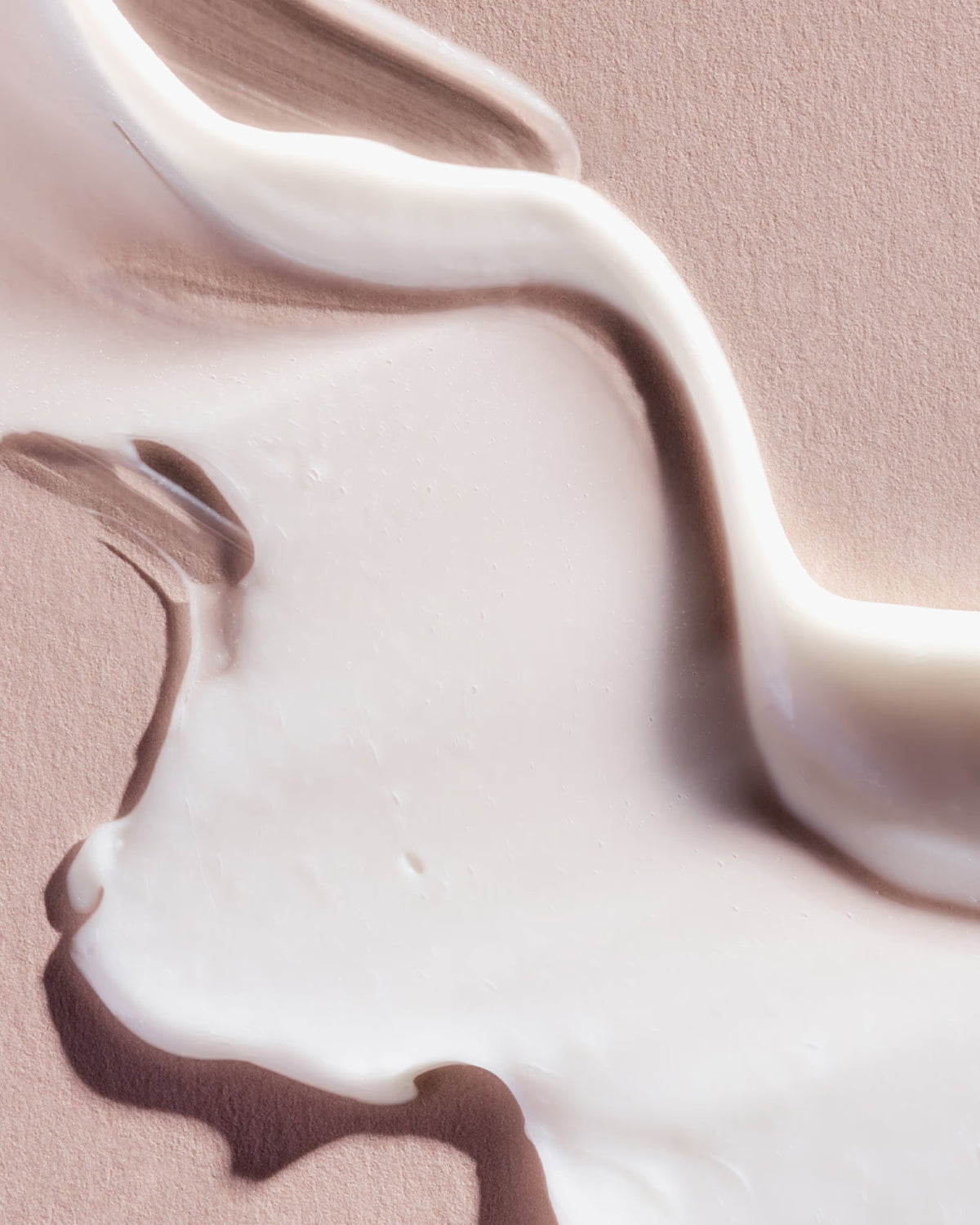 Close-up of white cream or paint on a pink background